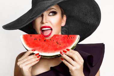 Mükemmel yüz ve kırmızı şapka bir karpuz yüzüne holding ile güzel kadın modeli