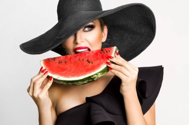 Mükemmel yüz ve kırmızı şapka bir karpuz yüzüne holding ile güzel kadın modeli