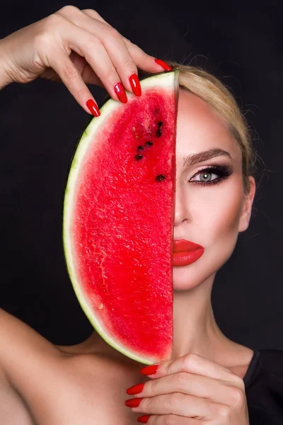 Modelo feminino bonito com rosto perfeito e cuidados com a pele lisa, segurando e comendo frutas de melancia — Fotografia de Stock