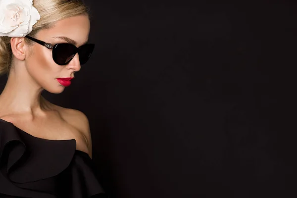 Retrato de mujer hermosa con cara impresionante con flor en el pelo y en maquillaje elegante, sobre fondo negro — Foto de Stock