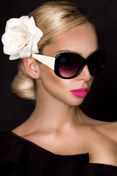 Retrato de mulher bonita com rosto deslumbrante com flor no cabelo e na maquiagem elegante, no fundo preto — Fotografia de Stock