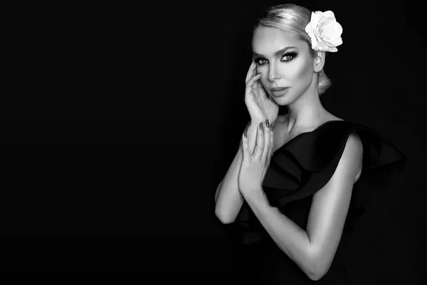 Retrato de mujer hermosa con cara impresionante con flor en el pelo y en maquillaje elegante, sobre fondo negro — Foto de Stock