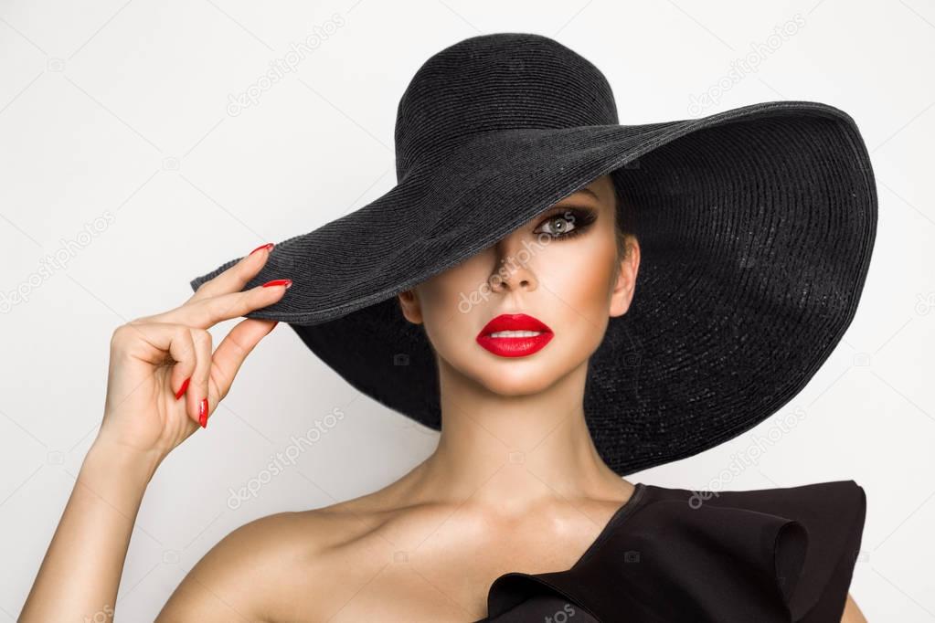 Portrait of an elegant woman in a hat and red lips on a white background