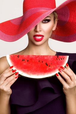 Mükemmel yüz ve kırmızı şapka bir karpuz yüzüne holding ile güzel kadın modeli