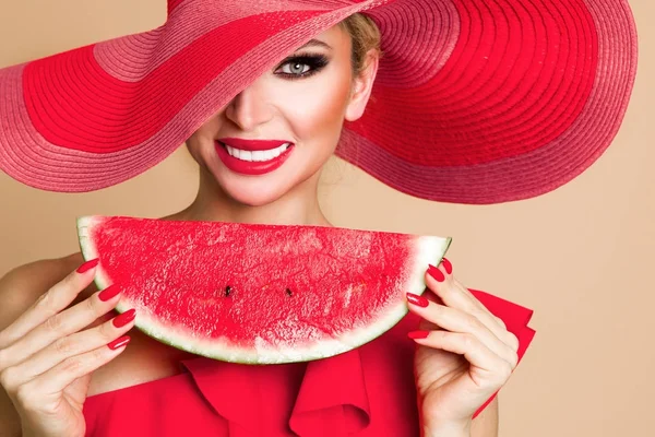 Modelo feminino bonito com rosto perfeito e chapéu vermelho segurando uma melancia em seu rosto — Fotografia de Stock