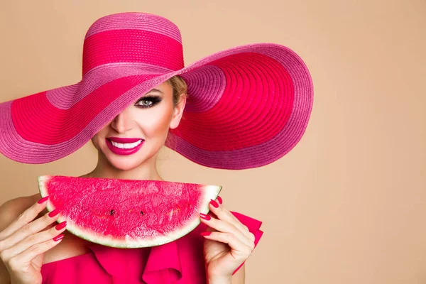 Modelo feminino bonito com rosto perfeito e chapéu vermelho segurando uma melancia em seu rosto — Fotografia de Stock