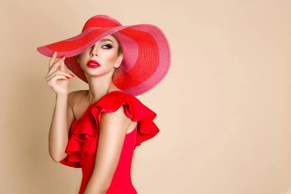 Ritratto di una donna elegante con cappello, bikini rosso e labbra rosse su sfondo beige — Foto Stock