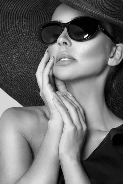Retrato de uma mulher elegante em um chapéu e óculos de sol em um fundo bege — Fotografia de Stock
