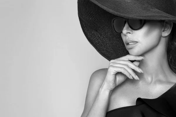 Retrato de una mujer elegante con sombrero y gafas de sol sobre fondo beige — Foto de Stock