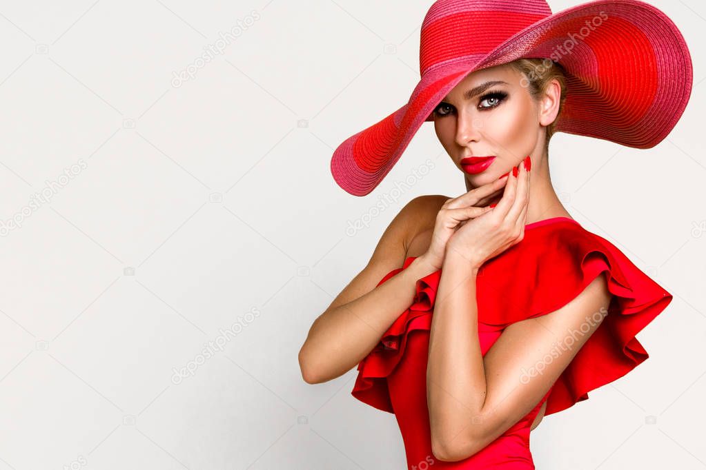 Portrait of an elegant woman in a hat, red bikini and red lips on a beige background
