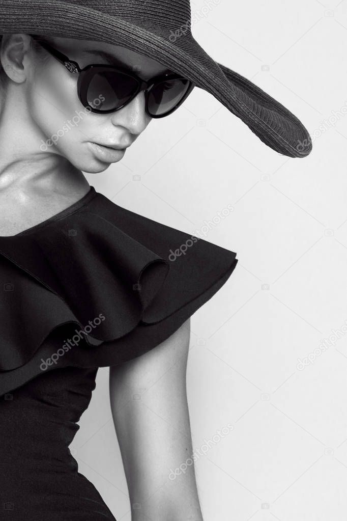 Portrait of an elegant woman in a hat and sunglasses on a beige background