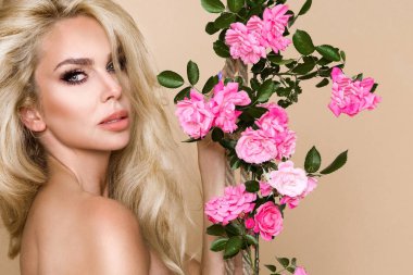 Gül çevrede uzun sarı saçlı güzel, gülümseyen kadın portresi