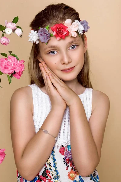 Doce, linda menina com uma grinalda de flores na cabeça, balançando em um balanço — Fotografia de Stock