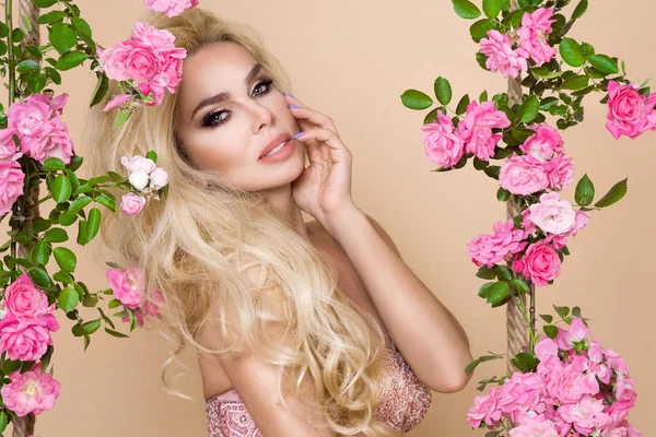 Portret van een mooie, lachende vrouw met lang blond haar rond de rozen — Stockfoto