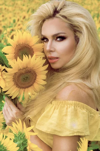 Красива блондинка стоїть на лузі з соняшниками і щасливо посміхається — стокове фото
