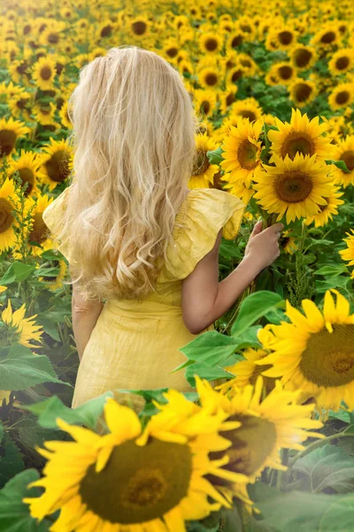 Piękna Blondynka kobieta stoi na łące z słoneczniki i uśmiecha się radośnie — Zdjęcie stockowe