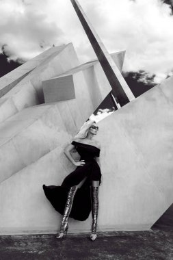 Şık moda modeli güzel siyah elbise ve altın uzun ayakkabı, şehrin arka planı seksi pozlar