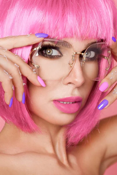 Hermosa modelo en peluca rosa y maquillaje de color con uñas de colores largos — Foto de Stock