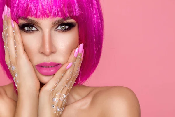 Hermosa modelo en peluca rosa y maquillaje de color con uñas de colores largos — Foto de Stock