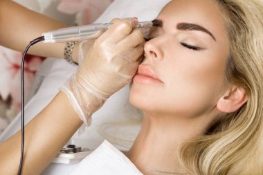 Ciltle bir güzellik içinde oturan düzgün, genç, güzel bir kadın. Bir güzellik kalıcı kaş kazançlar modelleme gerçekleştirir.