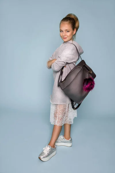 Linda niña vestida con ropa de escuela y mochila escolar de pie sobre fondo azul —  Fotos de Stock