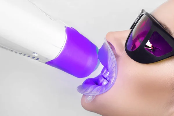 Genç güzel kadın güzel beyaz dişleri diş bir sandalyede oturuyor. Diş hekimi diş tedavileri.