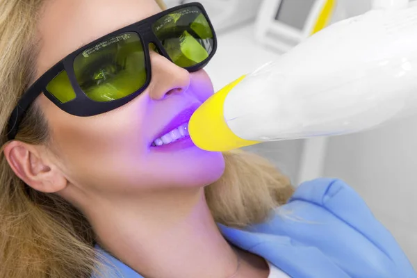 Genç güzel kadın güzel beyaz dişleri diş bir sandalyede oturuyor. Diş hekimi diş tedavileri.