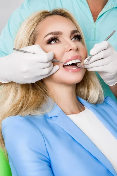 Młoda piękna kobieta z piękne białe zęby, siedząc na Fotel dentystyczny. Dentysta leczy zęby. — Zdjęcie stockowe