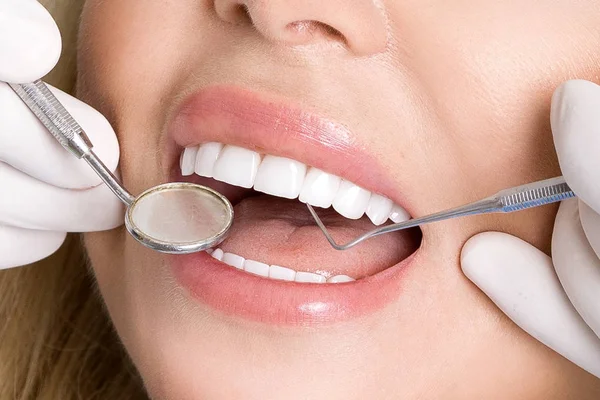 Mladá krásná žena s bělostnými zuby sedí na zubařském křesle. Zubař léčí zuby. — Stock fotografie
