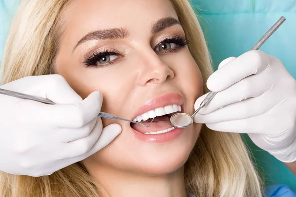 Młoda piękna kobieta z piękne białe zęby, siedząc na Fotel dentystyczny. Dentysta leczy zęby. — Zdjęcie stockowe