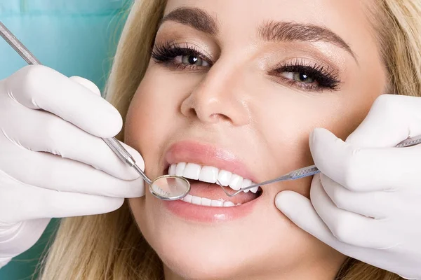 Młoda piękna kobieta z piękne białe zęby, siedząc na Fotel dentystyczny. Dentysta leczy zęby. — Zdjęcie stockowe