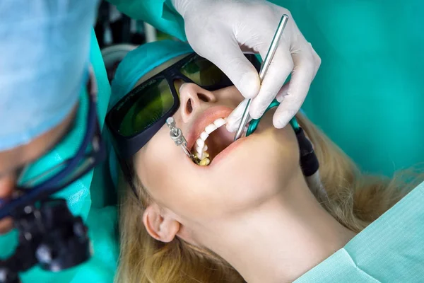 Genç güzel kadın güzel beyaz dişleri diş bir sandalyede oturuyor. Diş hekimi diş tedavileri.