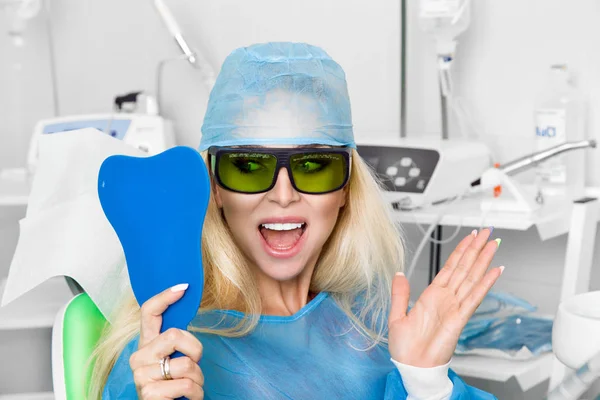 Genç güzel kadın güzel beyaz dişleri diş bir sandalyede oturuyor. Diş hekimi diş tedavileri.