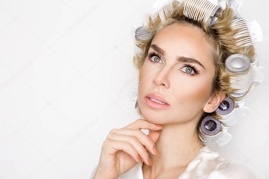 Beautiful blonde woman with hair rollers and in a bathrobe.
