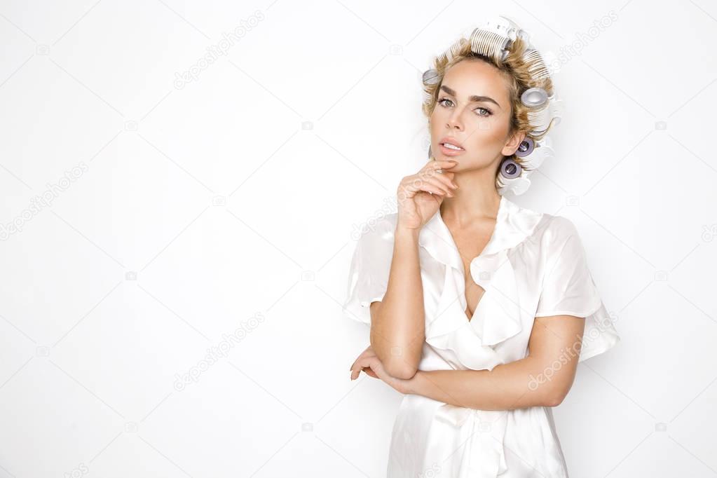 Beautiful blonde woman with hair rollers and in a bathrobe.