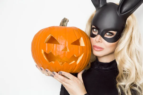 Bella giovane donna in costume coniglietto di Halloween, in piedi accanto a cesto pasquale e tenendo zucca — Foto Stock