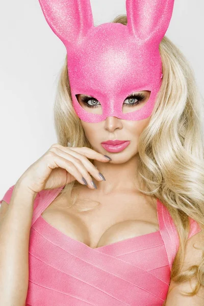 Bela sensual, jovem mulher em halloween traje rosa e máscara rosa, de pé sobre fundo branco — Fotografia de Stock