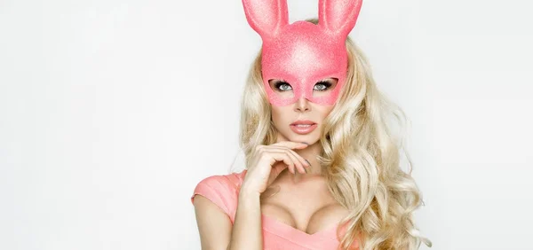 Mooie sexy, jonge vrouw in roze halloween kostuum en roze masker permanent op witte achtergrond — Stockfoto