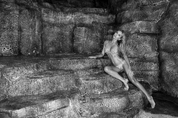 Linda, modelo feminino loira sexy em biquíni sexy deitado no fundo da cachoeira — Fotografia de Stock