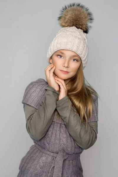 Linda niña vestida con ropa de invierno, sombrero y chaqueta de invierno con piel, de pie sobre fondo azul — Foto de Stock