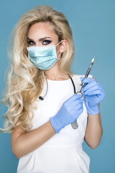 Enfermera rubia sexy con gafas, sosteniendo un estetoscopio y una jeringa . — Foto de Stock