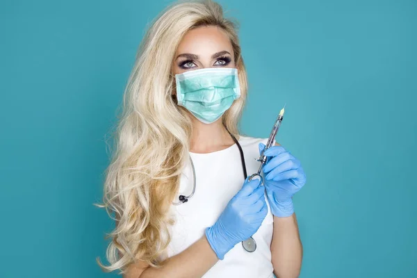 Enfermera rubia sexy con gafas, sosteniendo un estetoscopio y una jeringa . — Foto de Stock