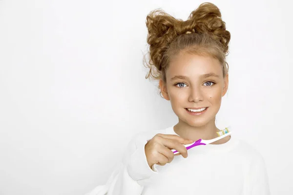 Bonita, linda loira, jovem segurando uma escova de dentes e sorrindo feliz. A rapariga está a lavar os dentes. . — Fotografia de Stock