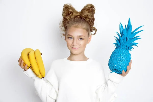 Carino, bella ragazza bionda con fiocco dai capelli. Bellezza e ragazza gioiosa, che tiene frutti colorati . — Foto Stock