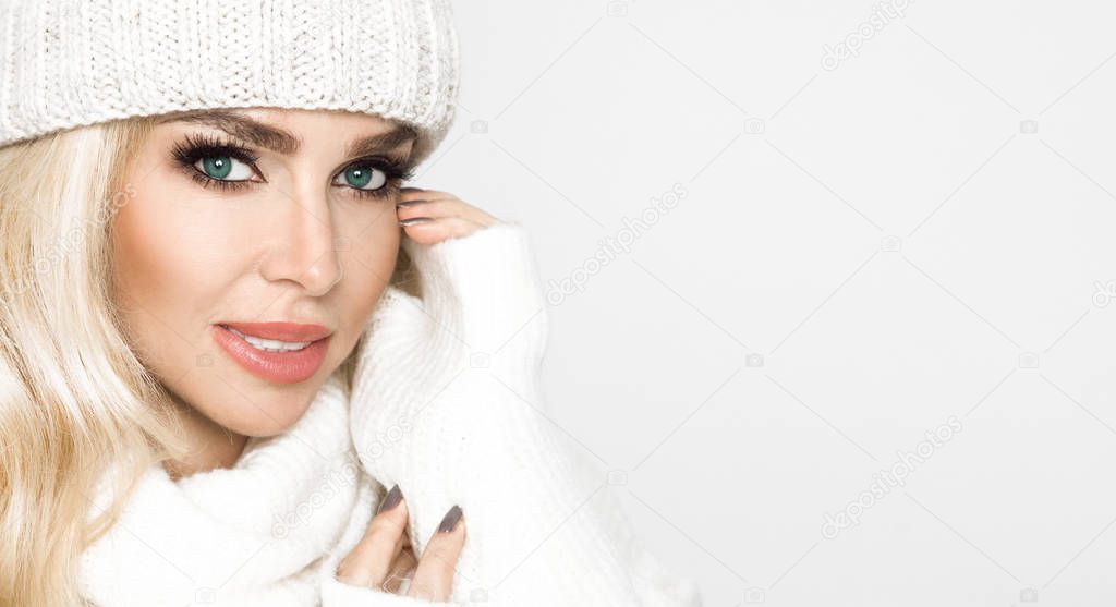 Portrait of beautiful woman with perfect face in winter cap and warm sweter. The model presents winter clothing.