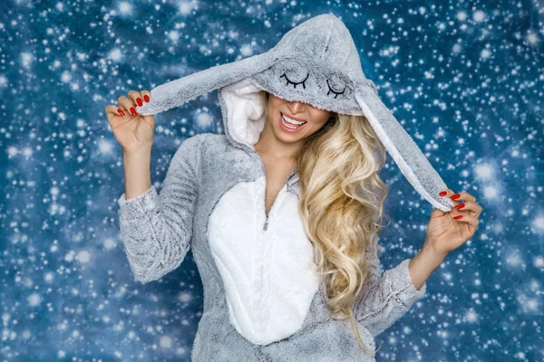 Mutlu bir şekilde gülümseyerek bir pijama, bir tavşan kostümü giyen güzel seksi sarışın kadın. Moda model bir kış arka plan üzerinde.