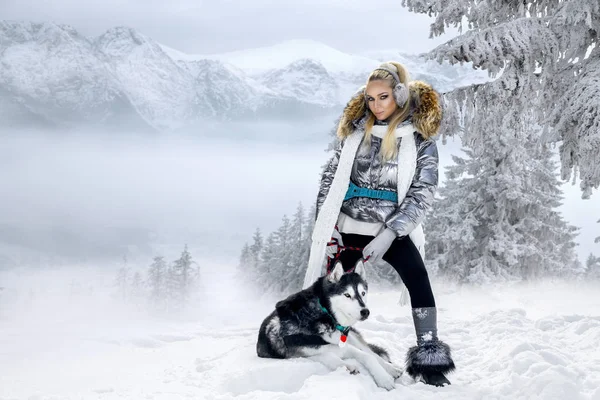 Piękna Blondynka Kobieta Stojąc Śniegu Trzyma Psy Husky Tle Jest — Zdjęcie stockowe