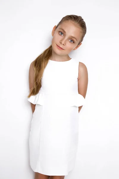 スタジオで白い背景の上に立っている白いエレガントなドレスにかわいい金髪女の子 — ストック写真