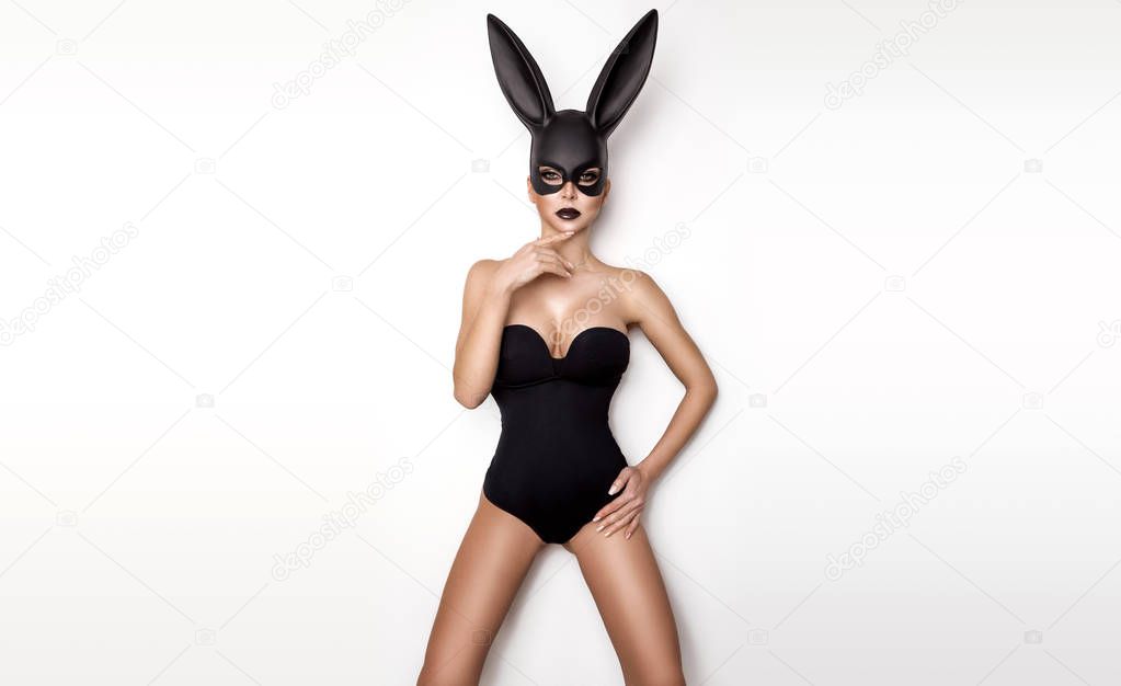 Sexy woman in a black bunny mask on a white background.