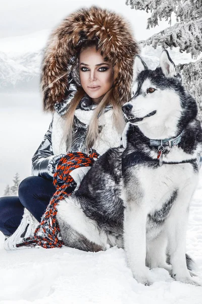 Happy young woman playing with siberian husky dogs in winter day.Attractive young woman with dog in wintertime outdoor. Amazing landscape.